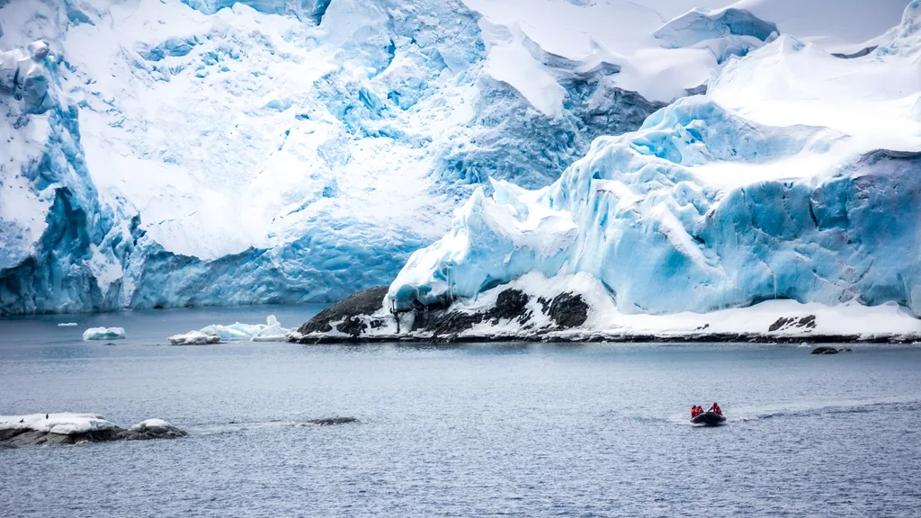 Boat on water beside large mountain covered in ice