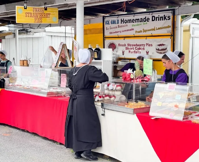 Women in plain dress selling homemade products at a flea market.