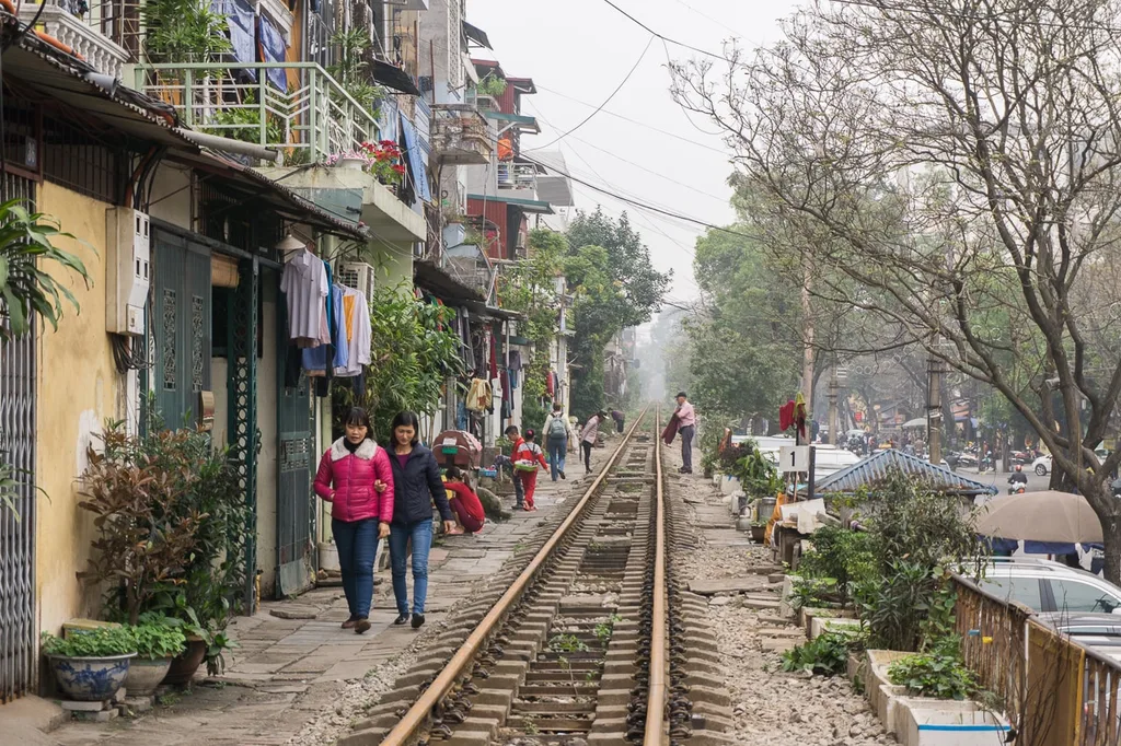 People walking between railway and houses