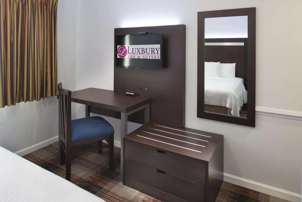 A neat room with a mirror and the caption Luxbury Inn and Suites.
